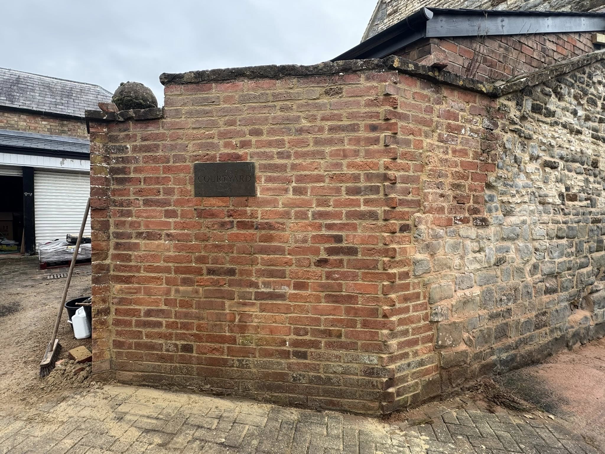 Brick corner with inset stone plaque, joining old stonework